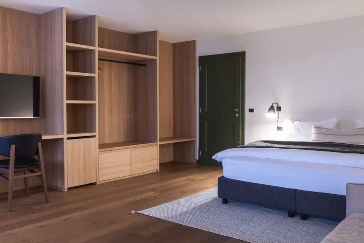 Quarto com cama, escrivaninha, cadeira, guarda-roupa e televisão.