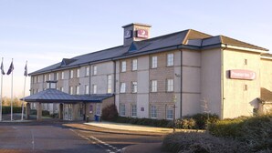 A hotel with a prominent Premier Inn sign, a covered entrance, and a parking area.