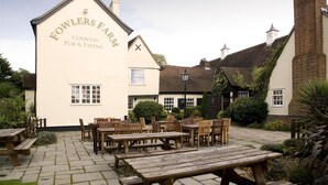 Un pub de campo con terraza y un cartel que dice 'Fowlers Farm Country Pub & Eating'.