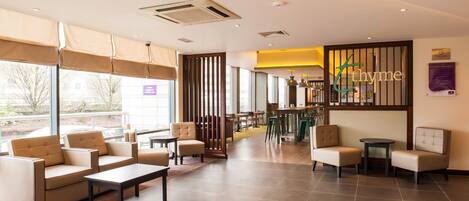 A modern lounge area with seating, a bar, and large windows.