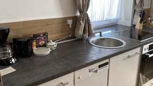 Eine moderne Küche mit eingebautem Geschirrspüler, Kaffeemaschine und Wasserkocher.