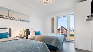 A modern bedroom with two beds, a large window, and a painting of a lighthouse. - Fischers Koje in the North Sea resort - with sauna, parking and WLAN (Büsum)