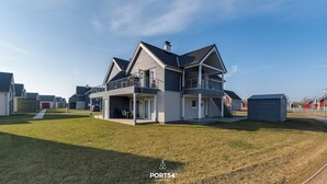 A modern two-story house with a balcony, a covered patio, and a small shed. - Fischers Koje in the North Sea resort - with sauna, parking and WLAN (Büsum)