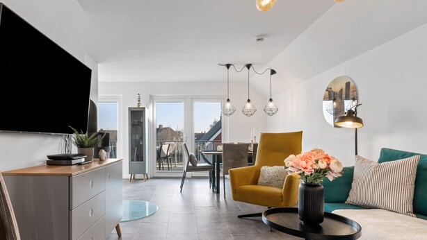 A modern living room with a sofa, armchair, and dining area. - Fischers Koje in the North Sea resort - with sauna, parking and WLAN (Büsum)
