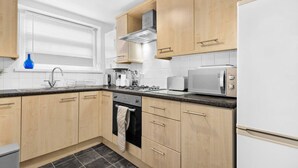 A modern kitchen with wooden cabinets, a stainless steel range hood, a microwave, and a built-in oven.
