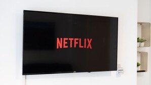 A flat-screen TV mounted on a white wall with the Netflix logo displayed.