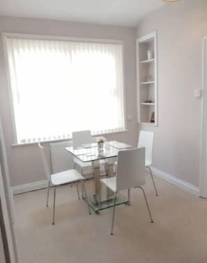 Cozy dining area with a glass-top table and four chairs, perfect for intimate meals.