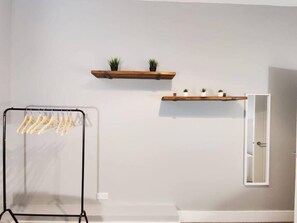 Simple, functional space with a drying rack, mirror, and potted plants.