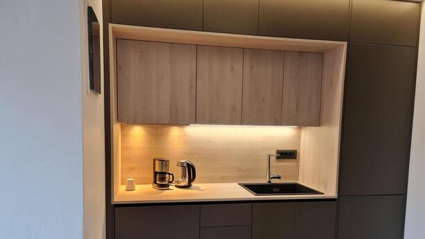 Een moderne keuken met een ingebouwde kookplaat, een spoelbak en een koffiezetapparaat op het aanrecht.