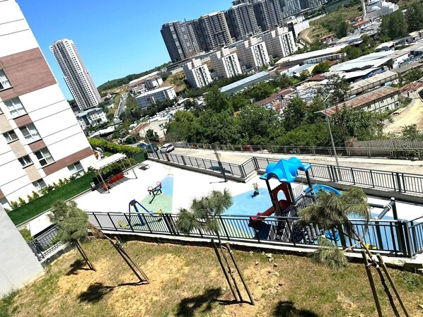 Ein Wohngebiet mit Schwimmbad, Spielplatz und Hochhäusern im Hintergrund.