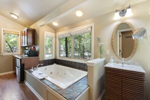 Un baño con bañera, tocador y ventanas.