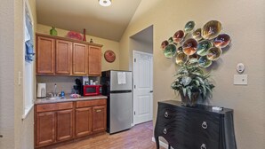 A kitchen with wooden cabinets, a refrigerator, a microwave, and a decorative glass bowl arrangement on the wall. - Royal Oak Treehouse with Jacuzzi (Eureka Springs)