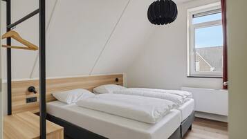 Un dormitorio con una cama litera, cabecera de madera, mesita de noche, lámpara colgante y ventana con vistas.