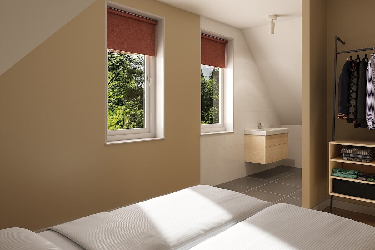 A bedroom with a bed, a wardrobe, a small bathroom, and two windows with red blinds.