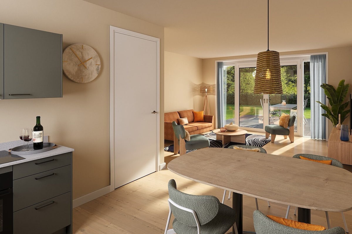 A modern kitchen with a dining area, a sofa, and a large window.