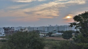 A cityscape with modern buildings, including a large white structure with a dome, under a sunset sky. - SSV TOP (Devanahalli)