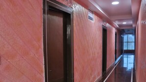 A long, narrow hallway with red walls and a shiny floor. - SSV TOP (Devanahalli)