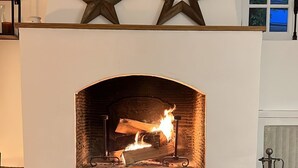 A fireplace with a stone base and a white mantel, flanked by two wooden stars. - Charming house in the heart of the Vexin Normand 1 hour from Paris and 20 mn from Giverny (Vexin-sur-Epte)