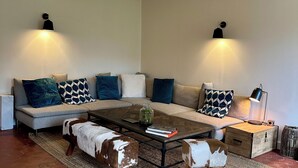 A modern living room with a sectional sofa, a coffee table, and two wall-mounted lamps. - Charming house in the heart of the Vexin Normand 1 hour from Paris and 20 mn from Giverny (Vexin-sur-Epte)
