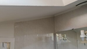 Een badkamer met betegelde muur, een spiegel en een glazen plank.
