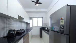 Una cocina moderna con encimera negra, electrodomésticos de acero inoxidable y un refrigerador con etiquetas de eficiencia energética.