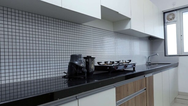 Een moderne keuken met witte kastjes, een zwart aanrecht en een betegelde spatwand.