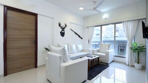 Una sala de estar moderna con un sofá blanco, una mesa de centro y un ventanal con cortinas.
