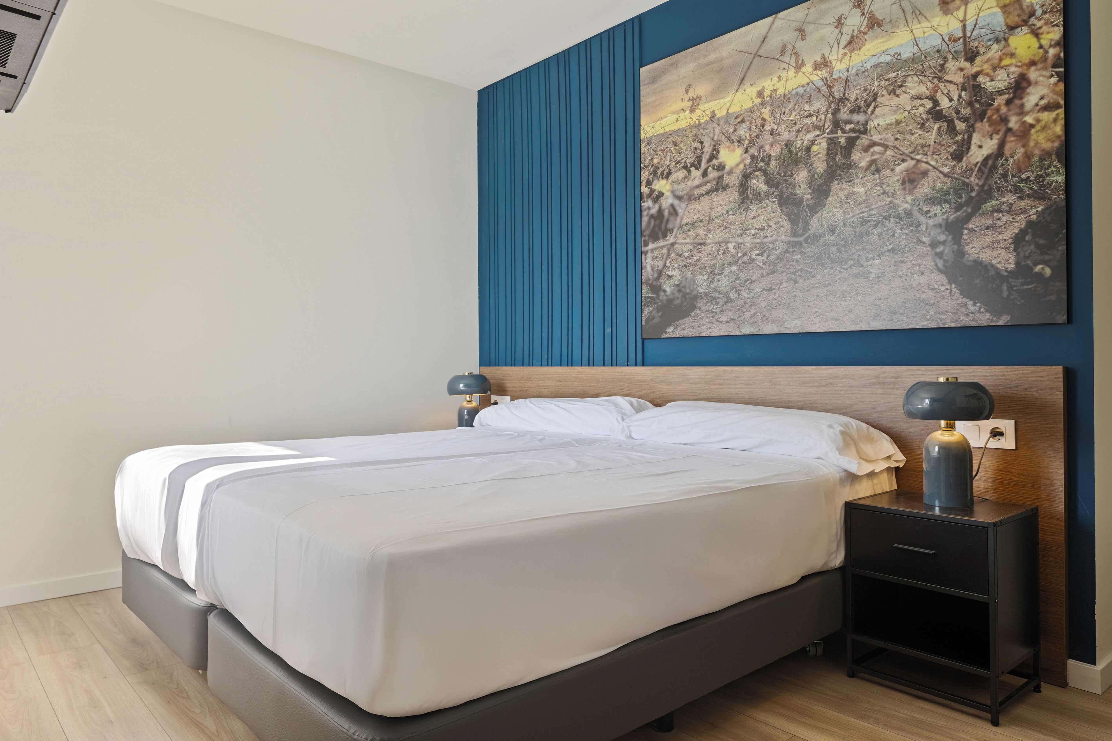Um quarto moderno com uma cama, mesas de cabeceira e um quadro pendurado na parede.