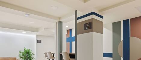 A modern interior with a reception desk, seating area, and a decorative wall.
