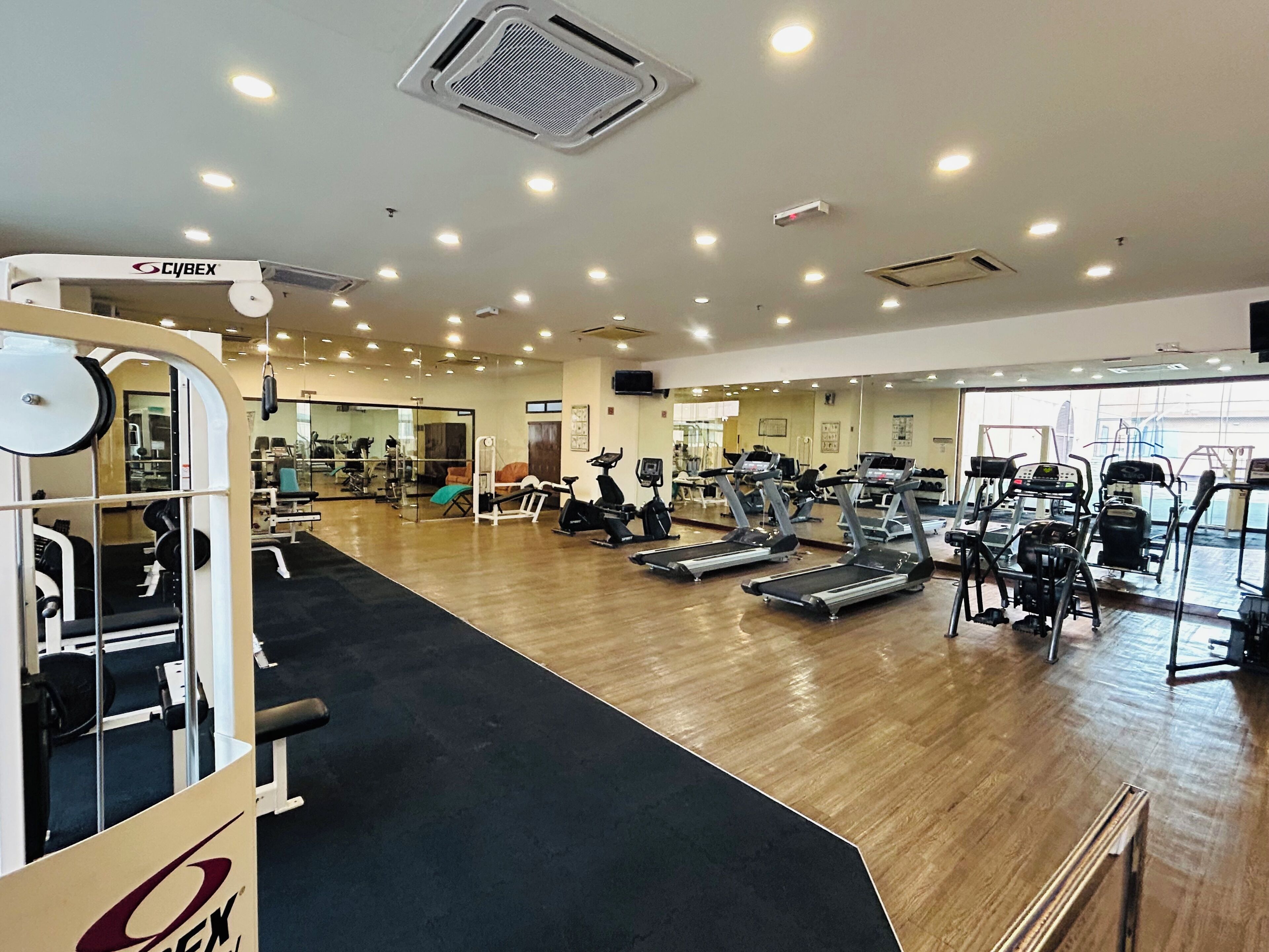 Une salle de sport équipée de divers appareils d’exercice, notamment des tapis de course et des appareils de musculation.
