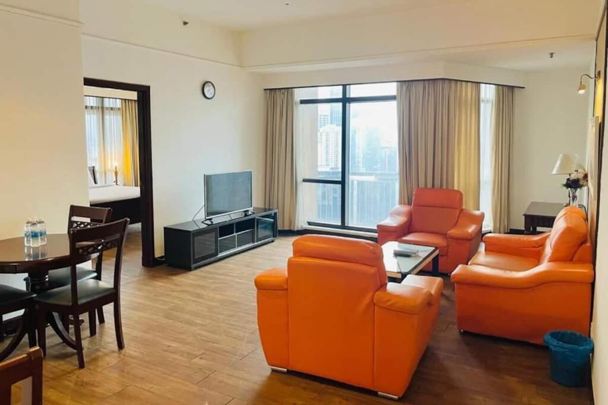A modern living room with orange sofas, a dining table, and a TV.