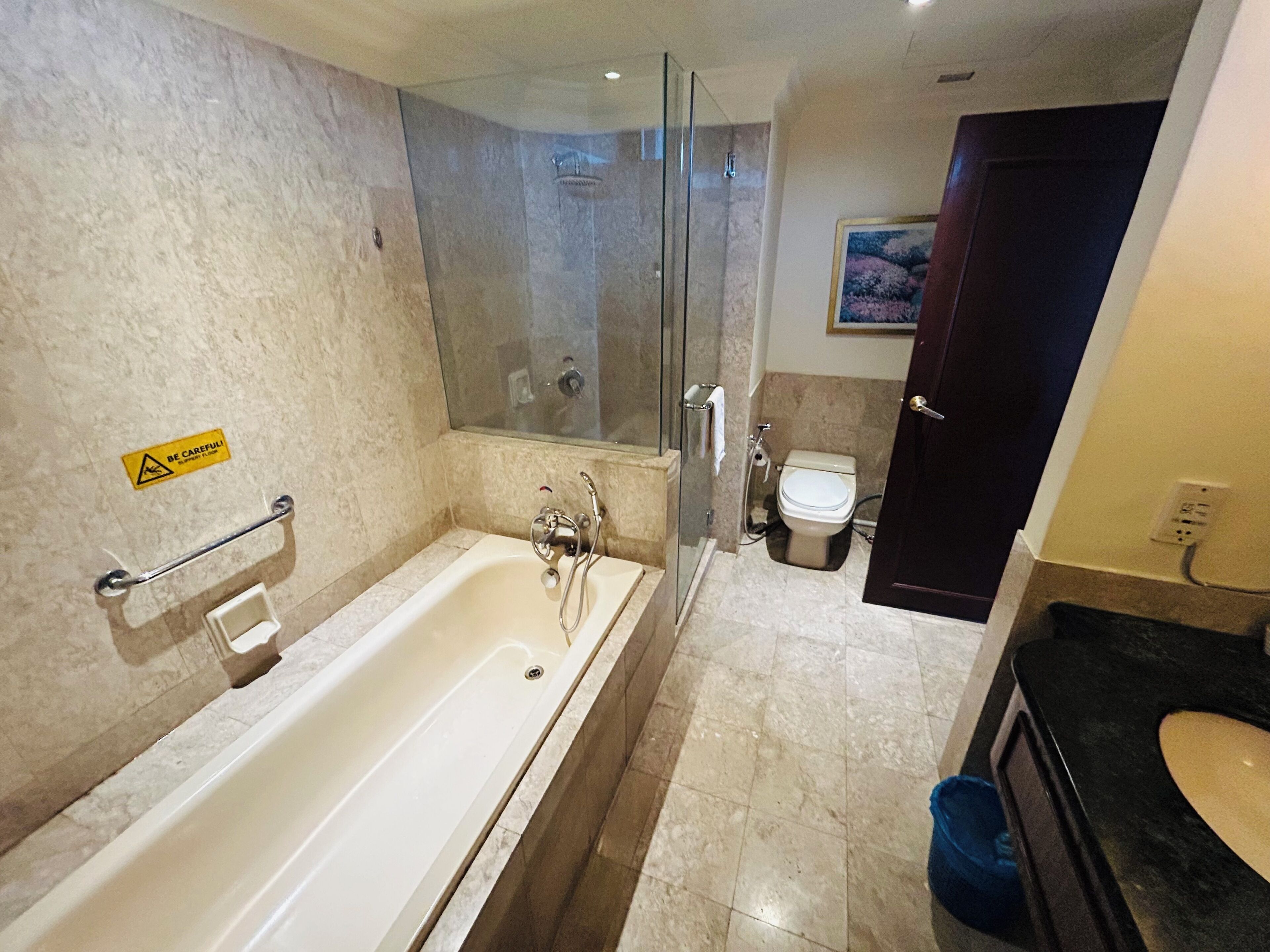 A modern bathroom with a bathtub, glass shower enclosure, toilet, and sink.