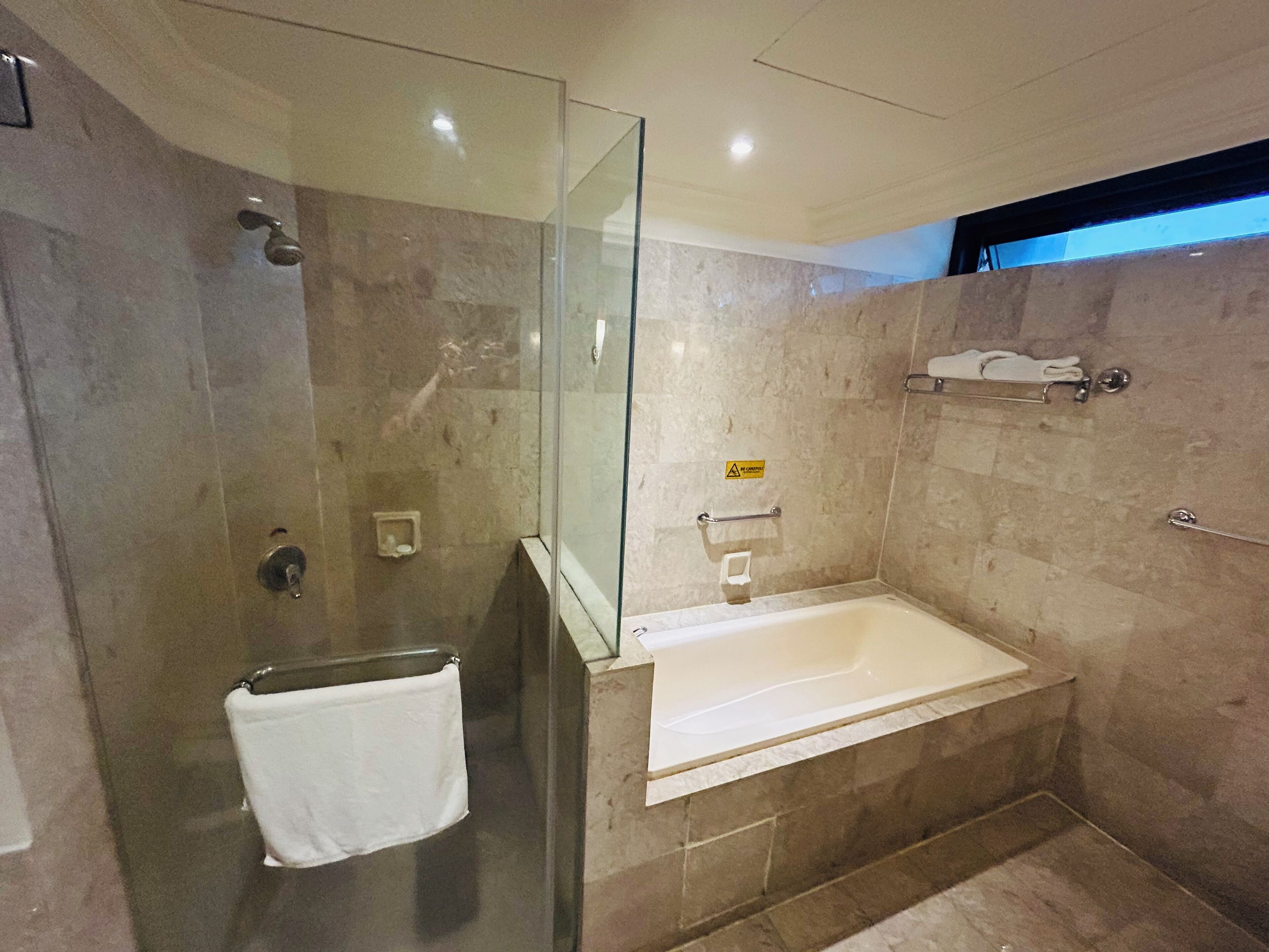 A modern bathroom with a glass-enclosed shower, a standalone bathtub, and a towel rack.