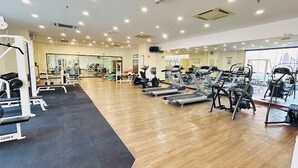 Une salle de sport équipée de tapis de course, d’appareils de musculation et d’un mur recouvert de miroirs.