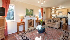 A cozy living room with a fireplace, a sofa, a coffee table, and a television.