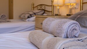 A hotel room with neatly made beds, two bedside lamps, and a bedside table with a lamp.
