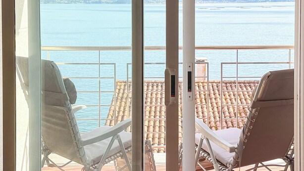 A balcony with two lounge chairs facing a sea view.