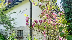 A building with a white exterior and a black roof, surrounded by lush greenery and flowering plants. - Beautiful private villa for 5 people with TV, balcony and pets allowed (Vairano)