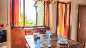 A wooden dining table with chairs, a chandelier, and a window with curtains. - Beautiful private villa for 5 people with TV, balcony and pets allowed (Vairano)