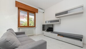 Un salon moderne avec un canapé gris, un téléviseur à écran plat et des étagères intégrées.