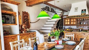 A dining area with a wooden table set for a meal, a bottle of wine, and a vase of flowers. - Beautiful apartment for 4 people with pool, WIFI, TV, patio, pets allowed and panoramic view (Orselina)