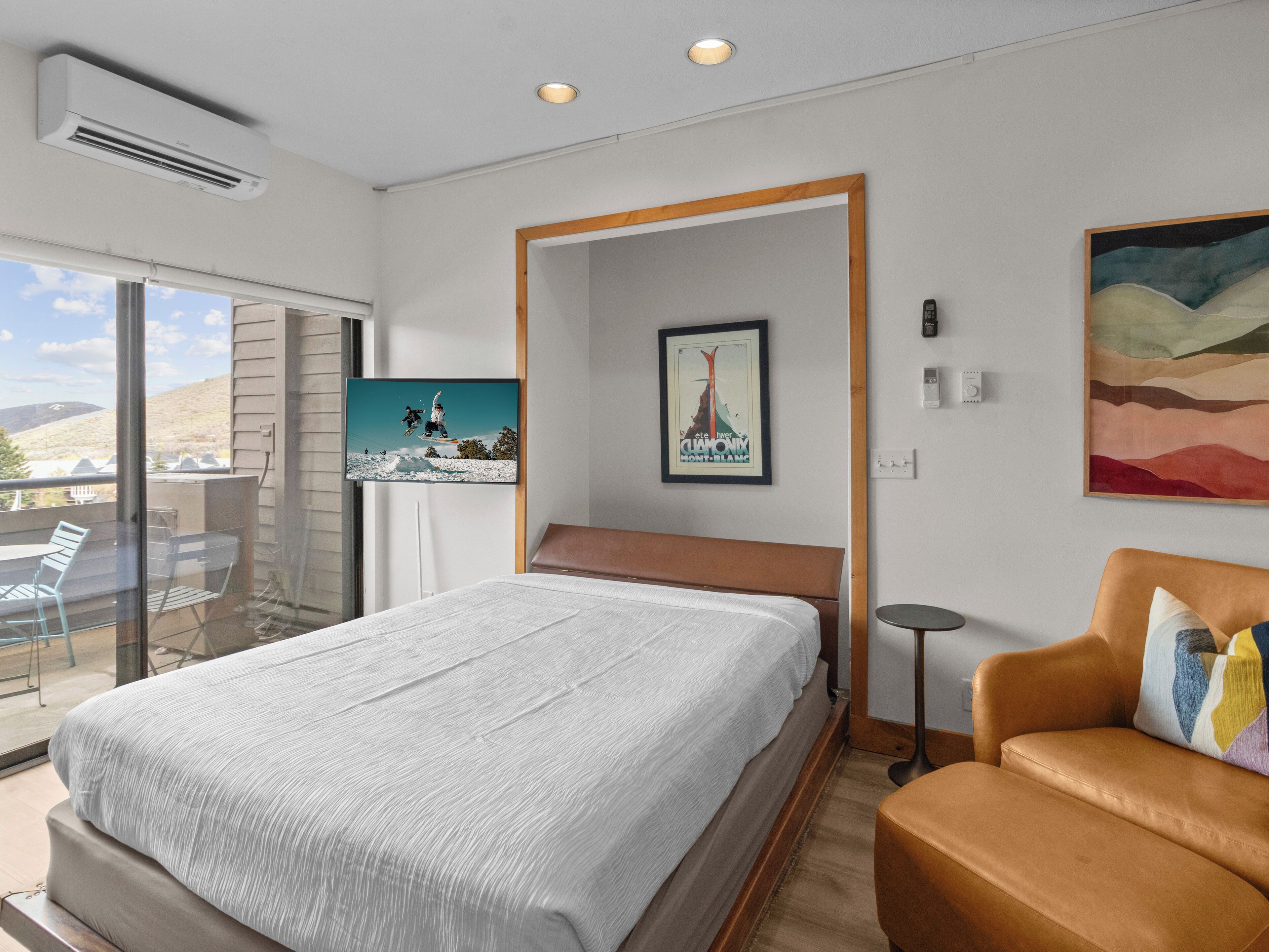 Et moderne hotelværelse med en stor seng, en balkon med udsigt, et lille skrivebord og et billede på væggen.