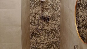 A shower with a floral tile backsplash, a handheld showerhead, and a wall-mounted faucet. - Home Sicily room2 (Pachino)