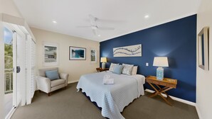 A bedroom with a bed, two nightstands, a ceiling fan, and artwork on the walls.