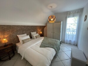 Un dormitorio ordenado con cama, lámparas de noche, armario y ventana con cortinas.