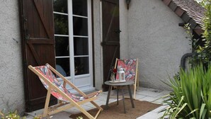Dos sillones de madera con tapicería colorida frente a un edificio con puerta y ventana blancos.