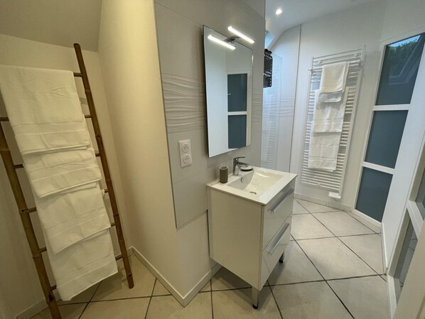 Ein modernes Badezimmer mit Waschbecken, Spiegel und Handtuchhalter.