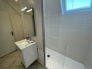 Un baño moderno con lavabo blanco, espejo y cabina de ducha.