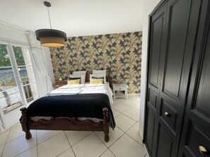 Ein Schlafzimmer mit Bett, Nachttisch, Kleiderschrank und einem Fenster mit Vorhängen.