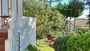 Un sendero estrecho que conduce a un edificio de fachada blanca y un pequeño jardín.